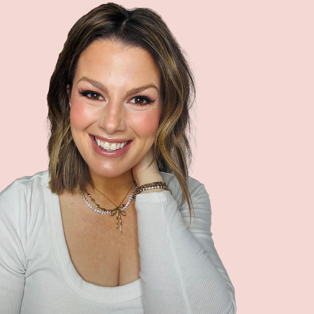 An image of a woman casually sitting and wearing jewelry around her neck and on her wrists.