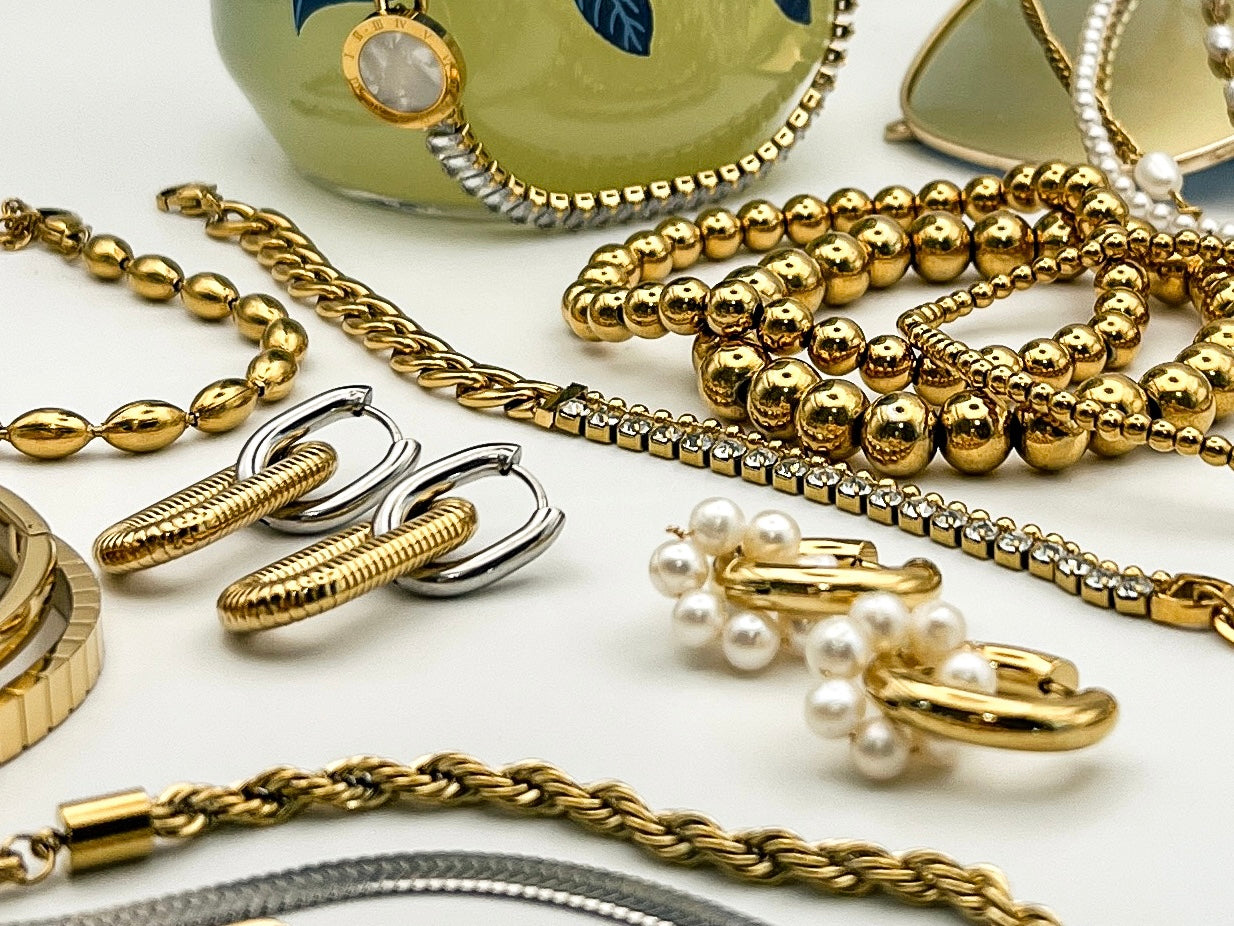 An assortment of gold jewelry items laying together on a white surface