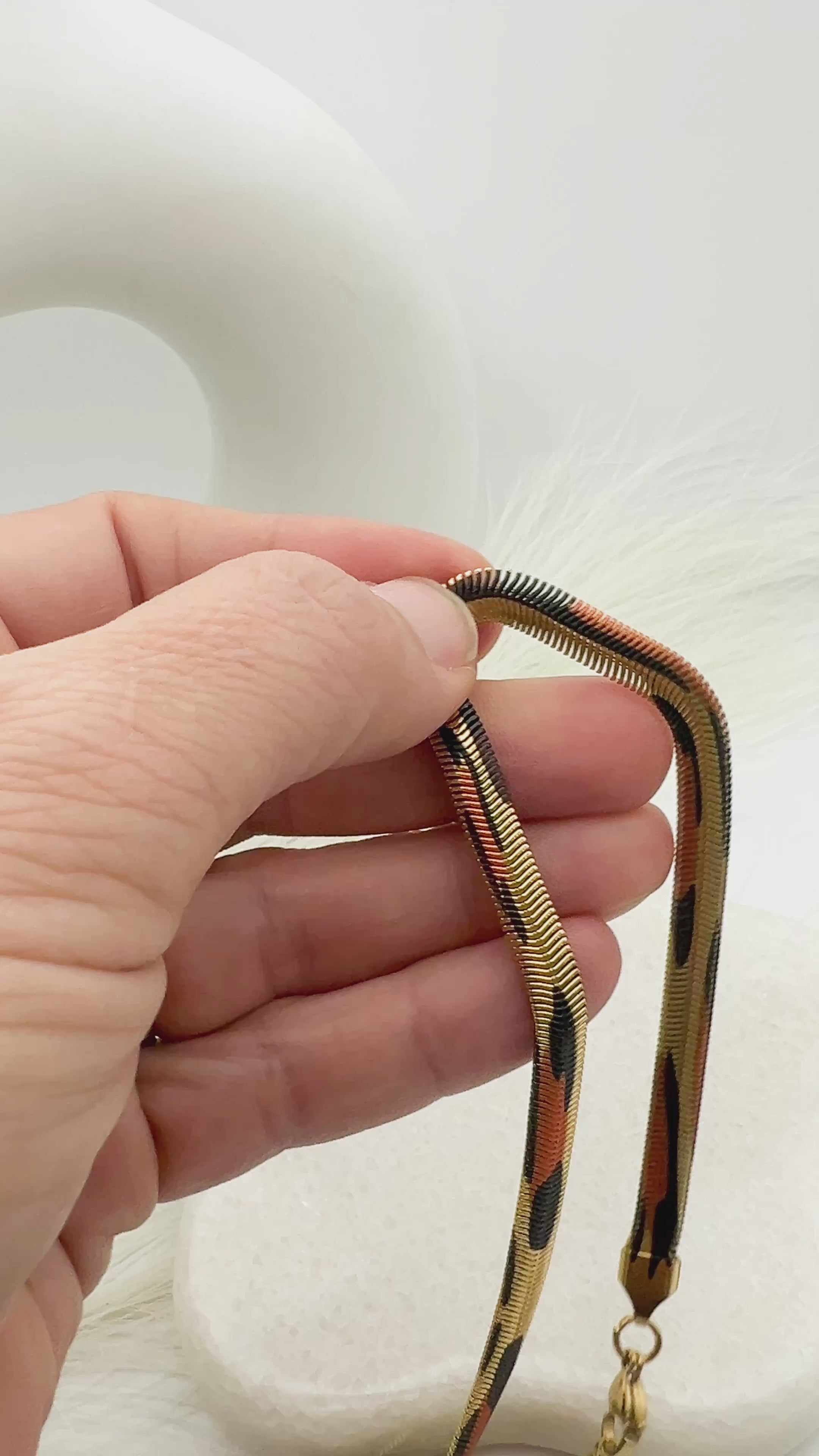A video of a hand holding up the leopard colored necklace